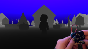 A darkly lit 3D world is shown on screen alongside a person's hands holding a micro:bit.